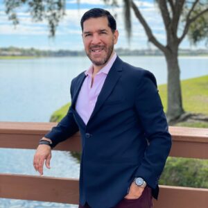 a man wearing a suit leaning on a wooden railing