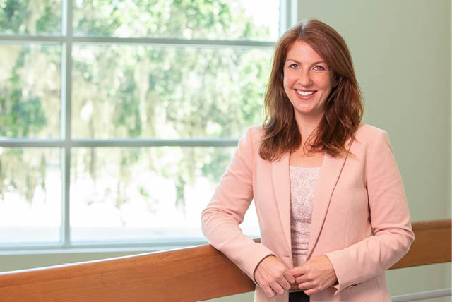 A woman smiling while standing near a window