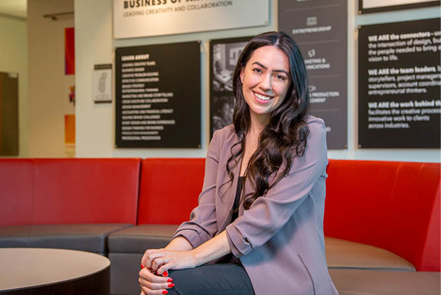 A smiling woman sitting in front of signs on a wall