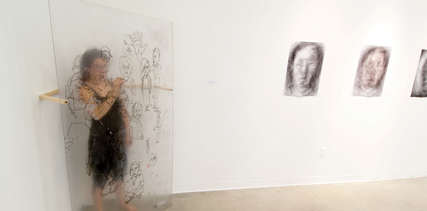 A woman standing behind frosted glass drawing with a marker