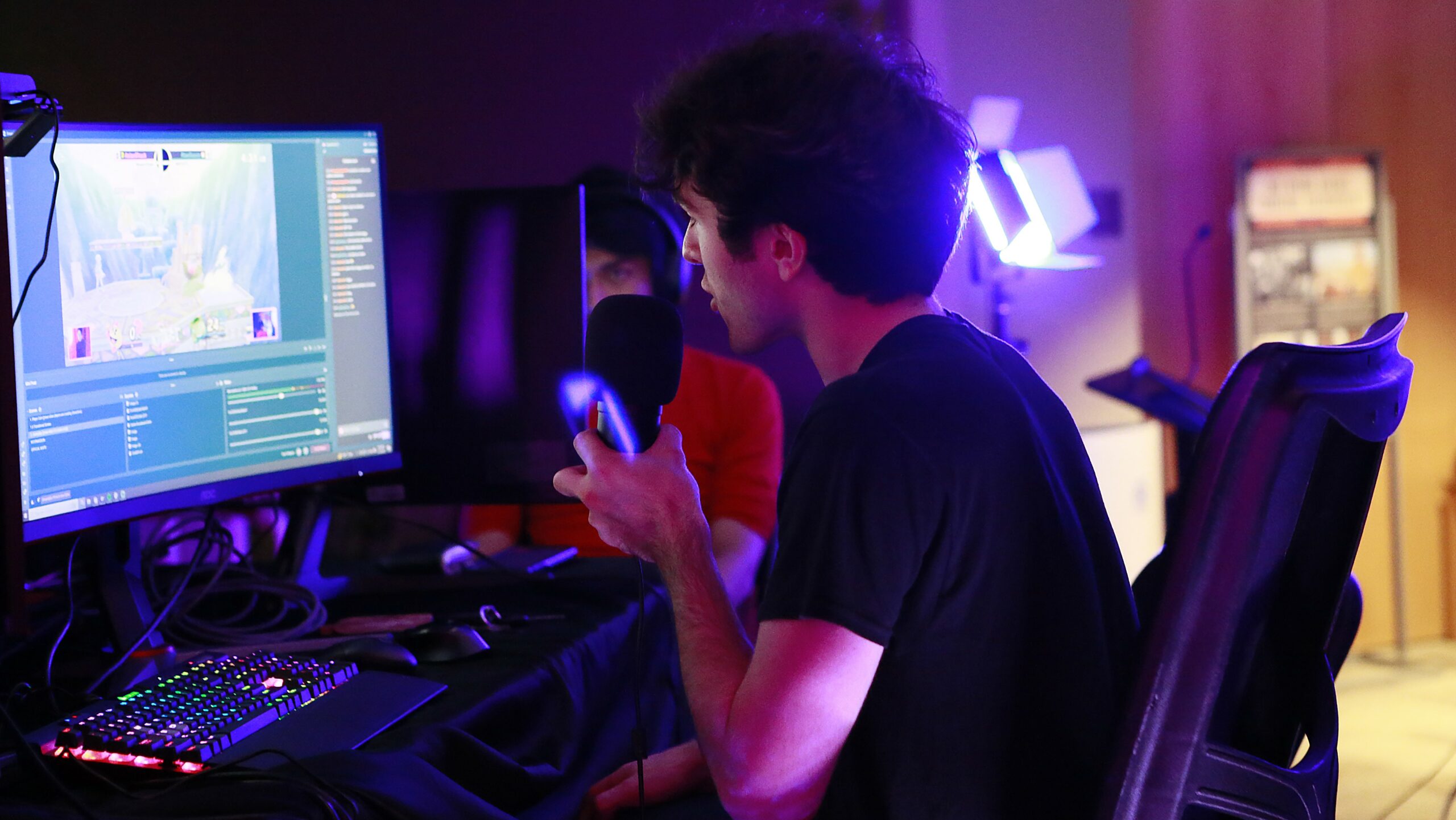 A boy sits at a computer playing a competitive esports match.