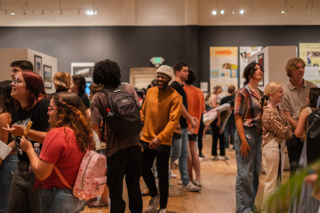 A gallery full of people to view the work at the annual juried exhibition.