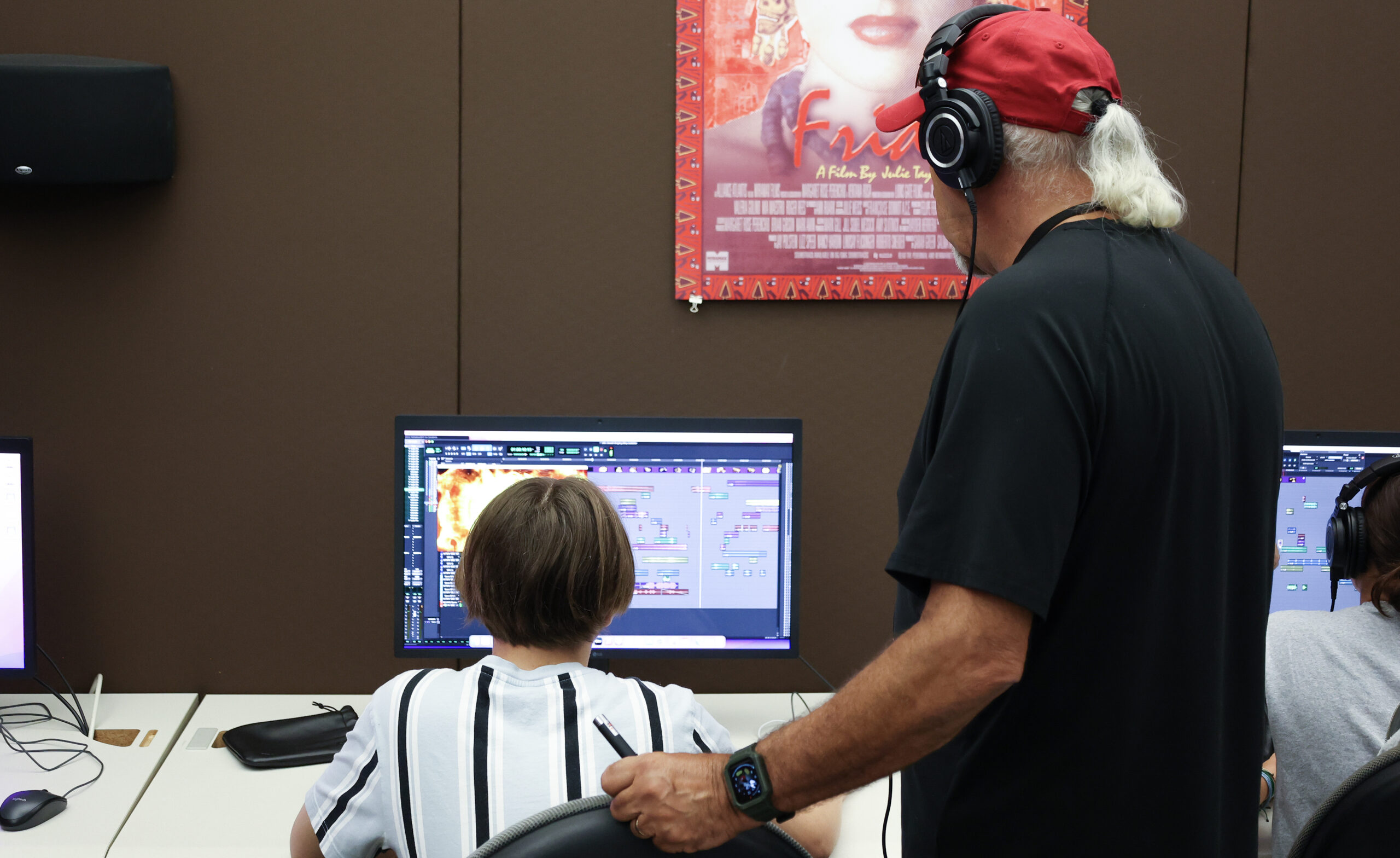 A faculty member looking over the shoulder of a young student who is working on the computer.