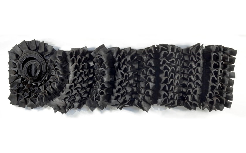 Artistic sculpture on a white wall made of black rubber tires.