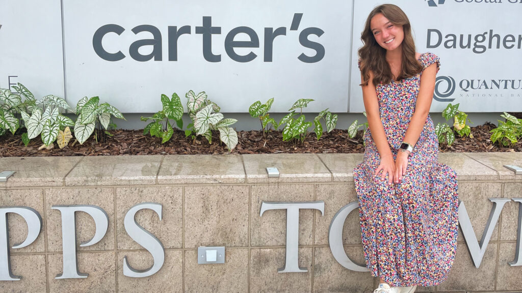 Woman sitting on a ledge outside of the corporate office for Carter’s.