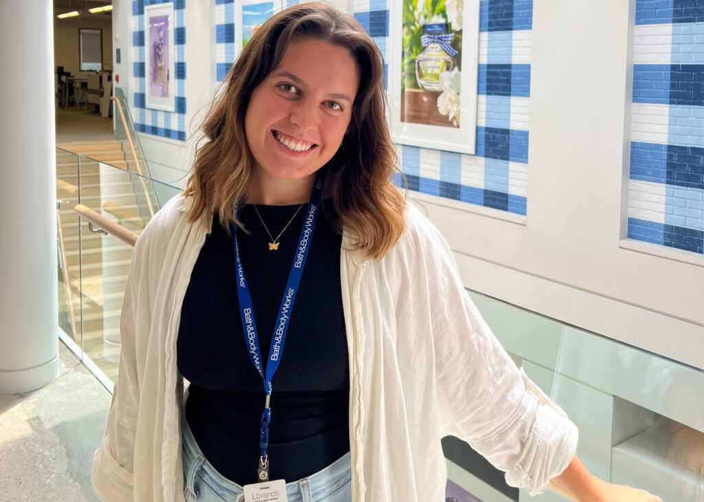 A woman poses in front of a building with blue tile placed in a plaid pattern.