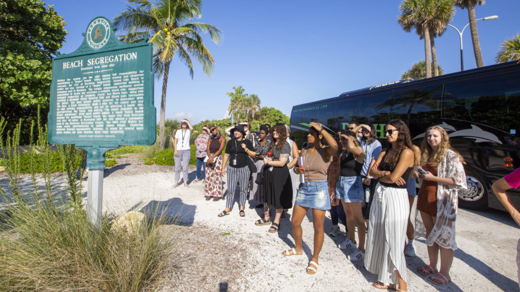 Students, faculty, and staff gather around a historic marker at Lido Beach.