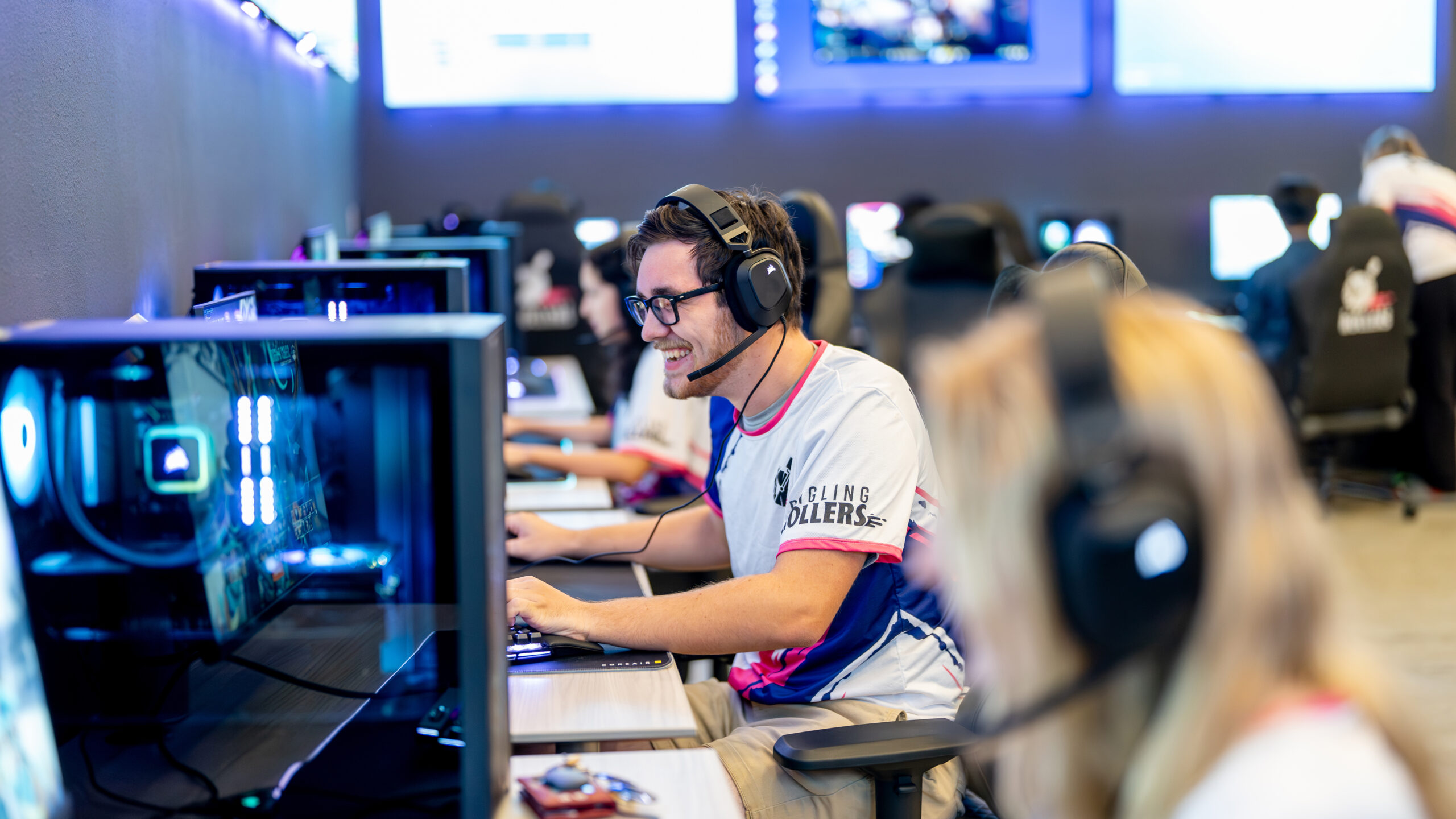 Male student wears a headset and is seated at an esports gaming station