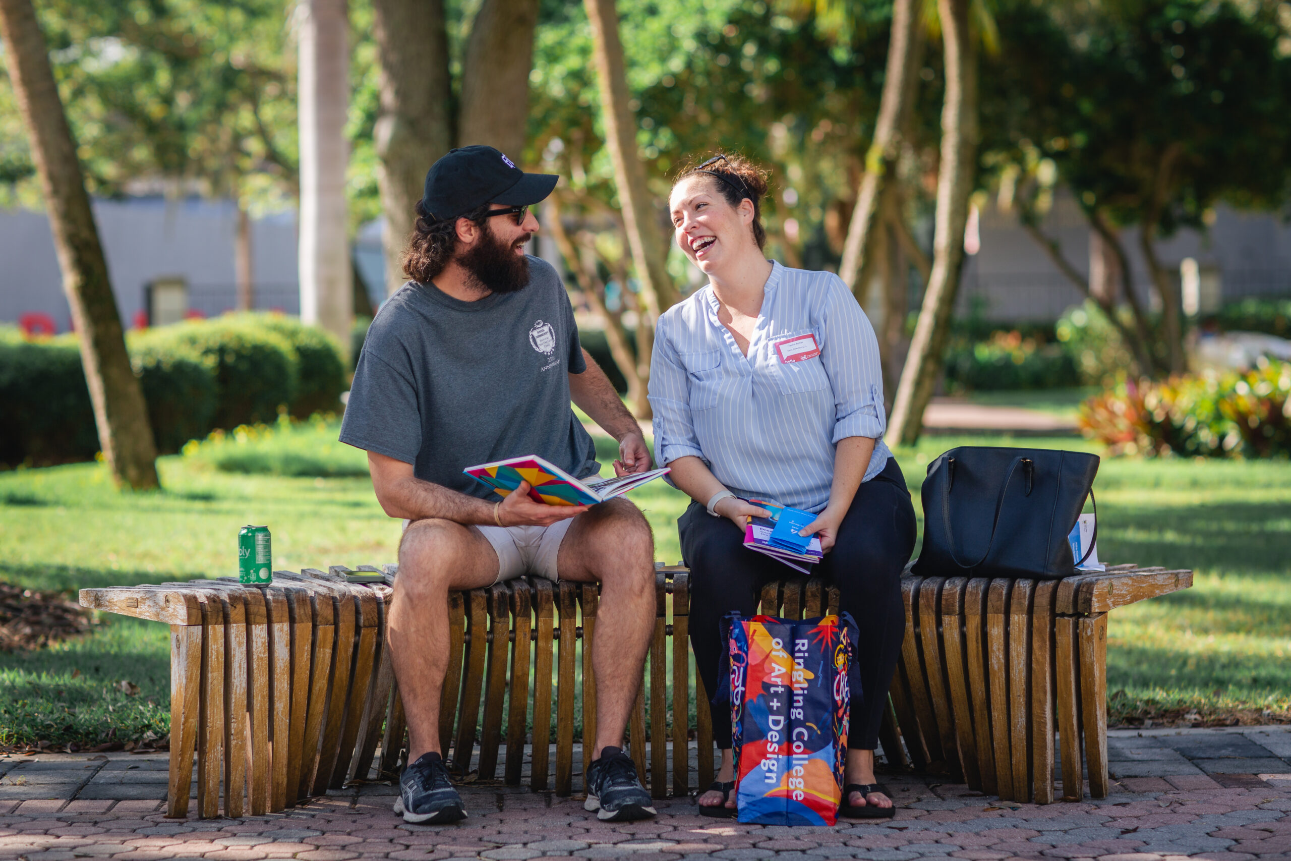 A man and woman sit outside on a bench and laugh together.