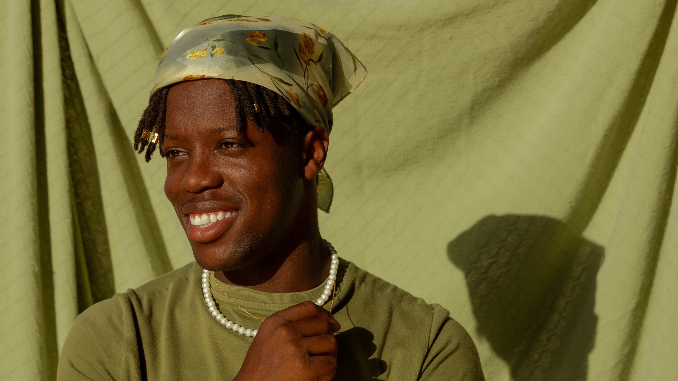 Headshot of a young Black man, Jesse Clark, wearing a headscarf.