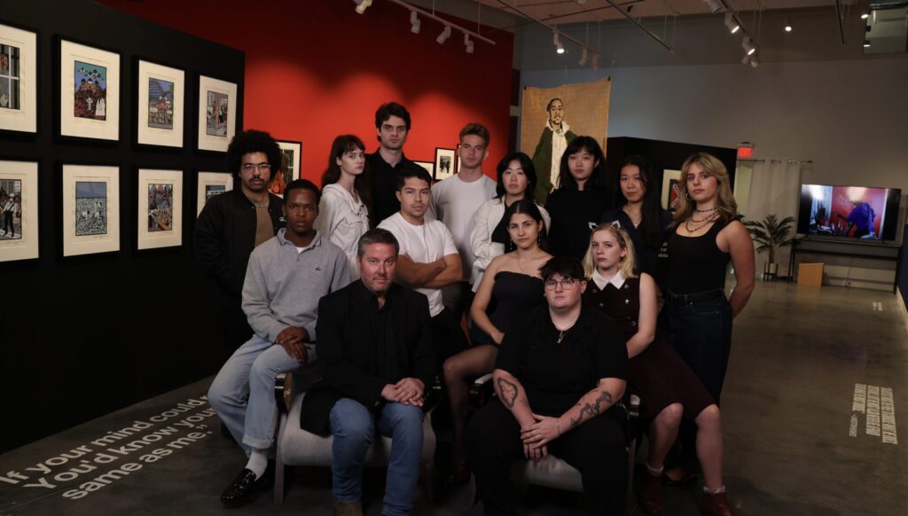 A group of college students pose in a gallery.