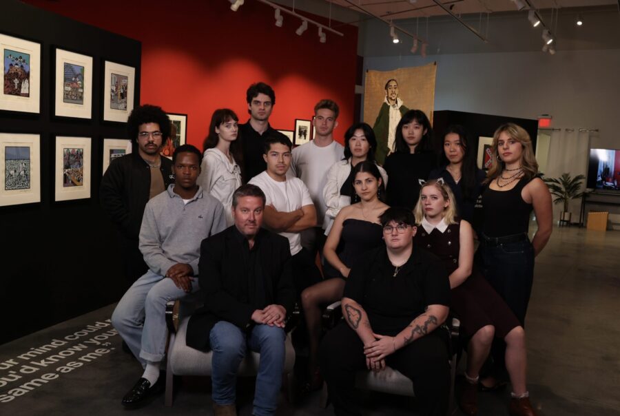 A group of college students pose in a gallery.