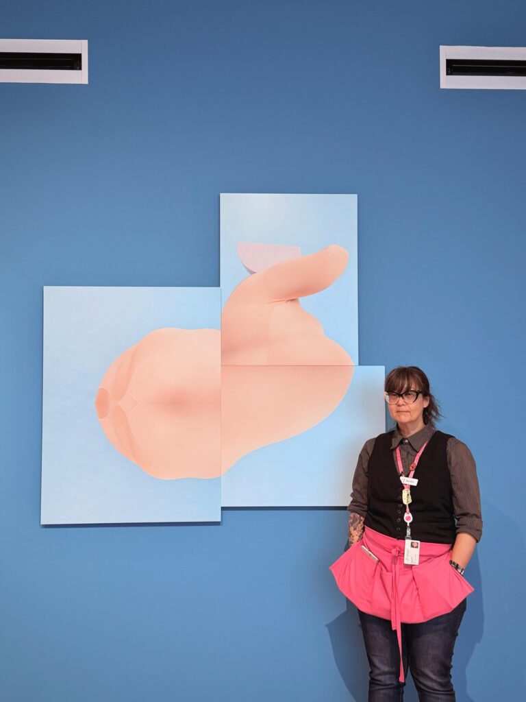 woman in pink apron in front of art