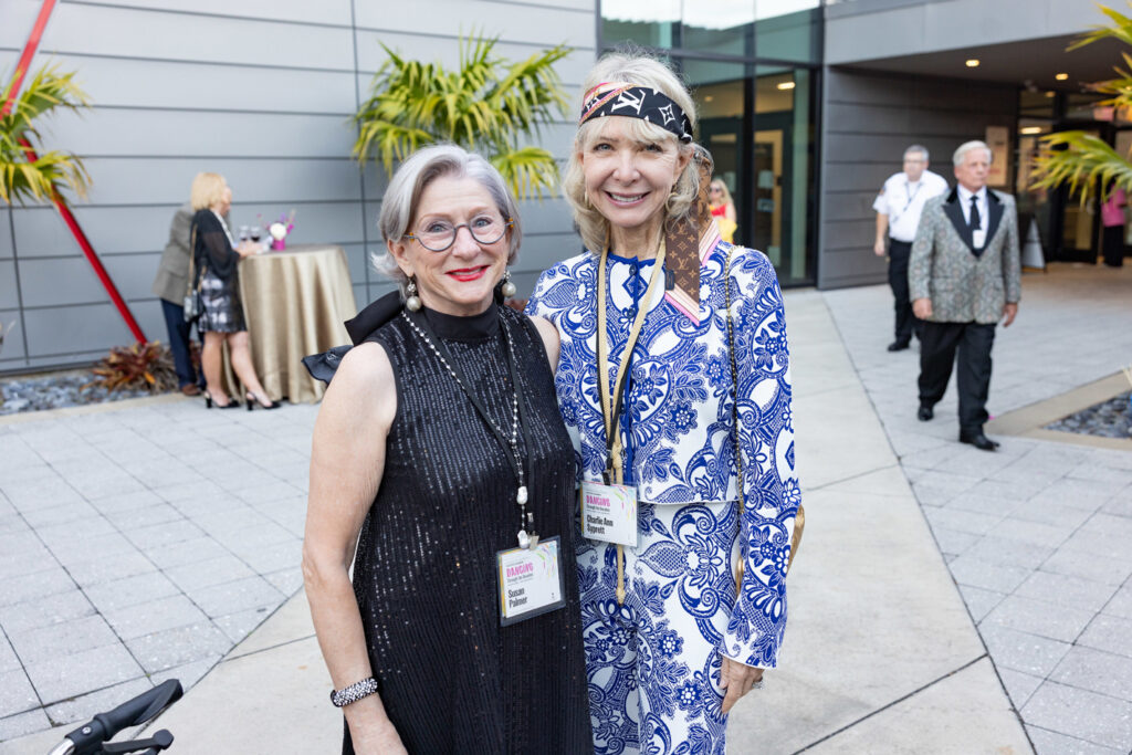 Alumni Friends at Reception Two alumni smiling and posing together at an outdoor campus reception.