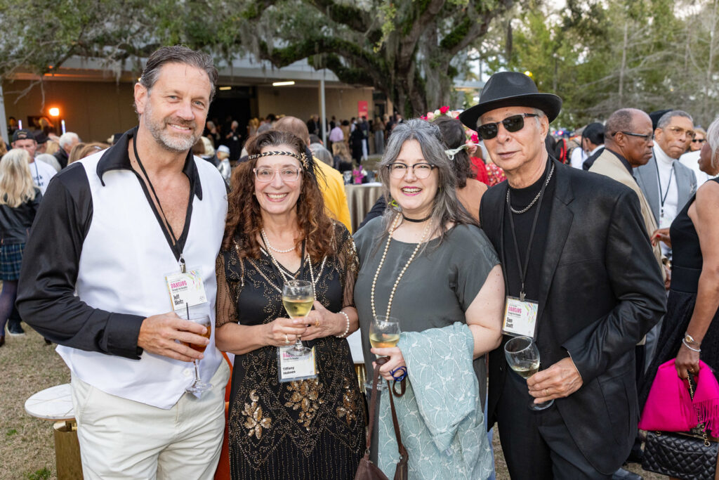 Alumni Gathering at Outdoor Event Group of alumni posing together at an outdoor campus event with drinks and name badges.