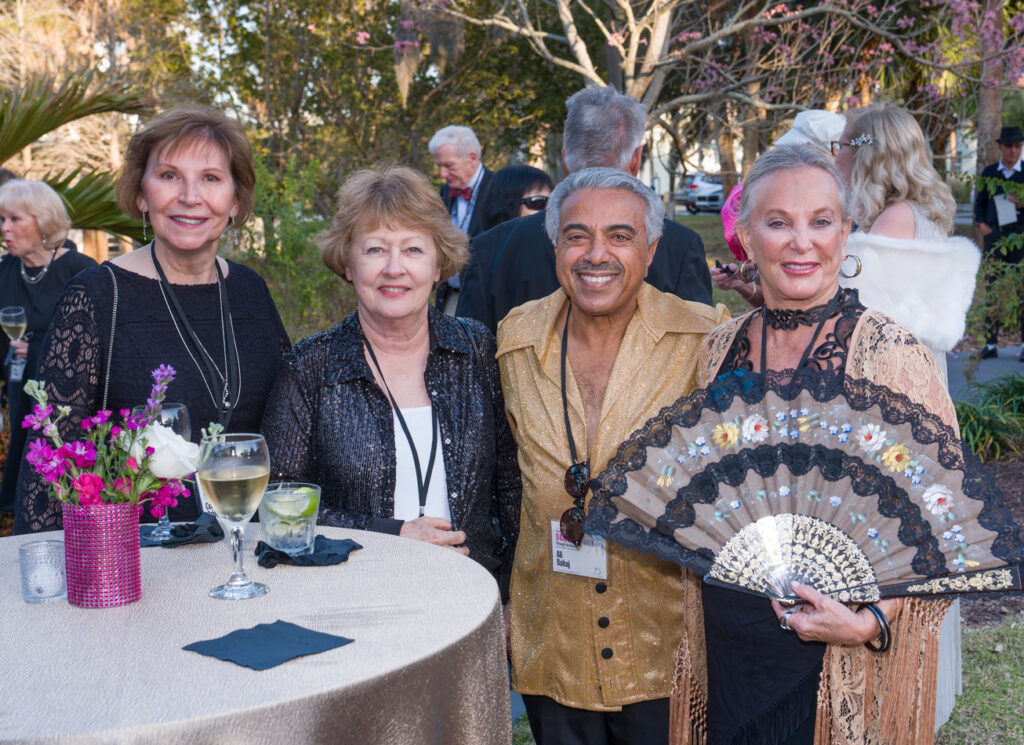 Alumni Group at Social Event Group of alumni gathered around a table at an outdoor campus event.