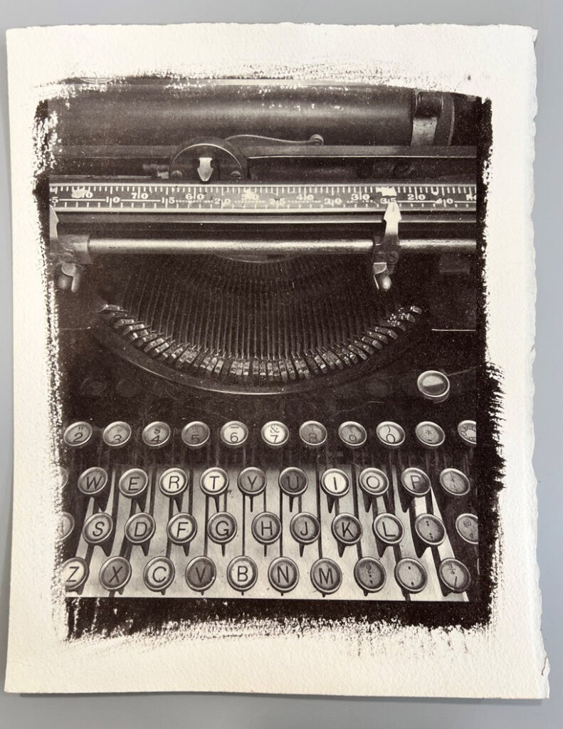 Black-and-white photographic print of a vintage typewriter with detailed keys and textured edges