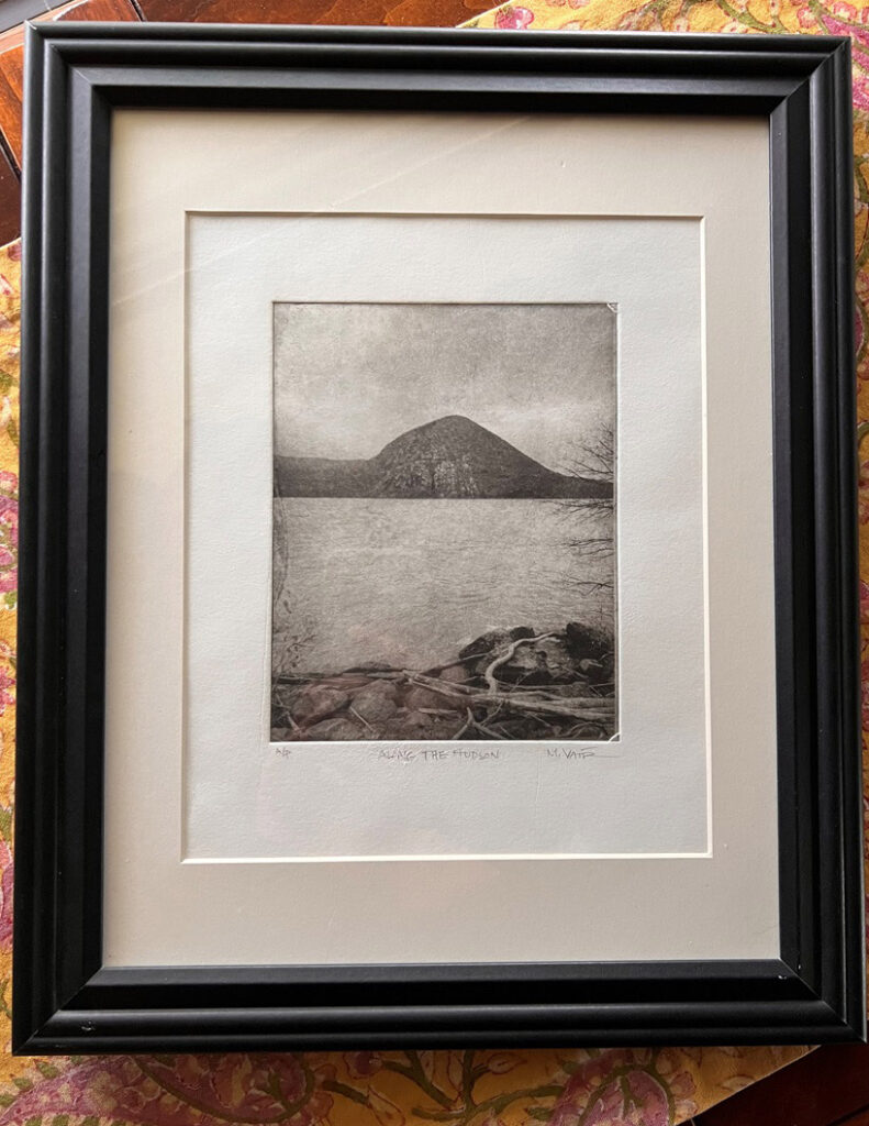 Framed black-and-white landscape print featuring a distant hill or mountain across a body of water