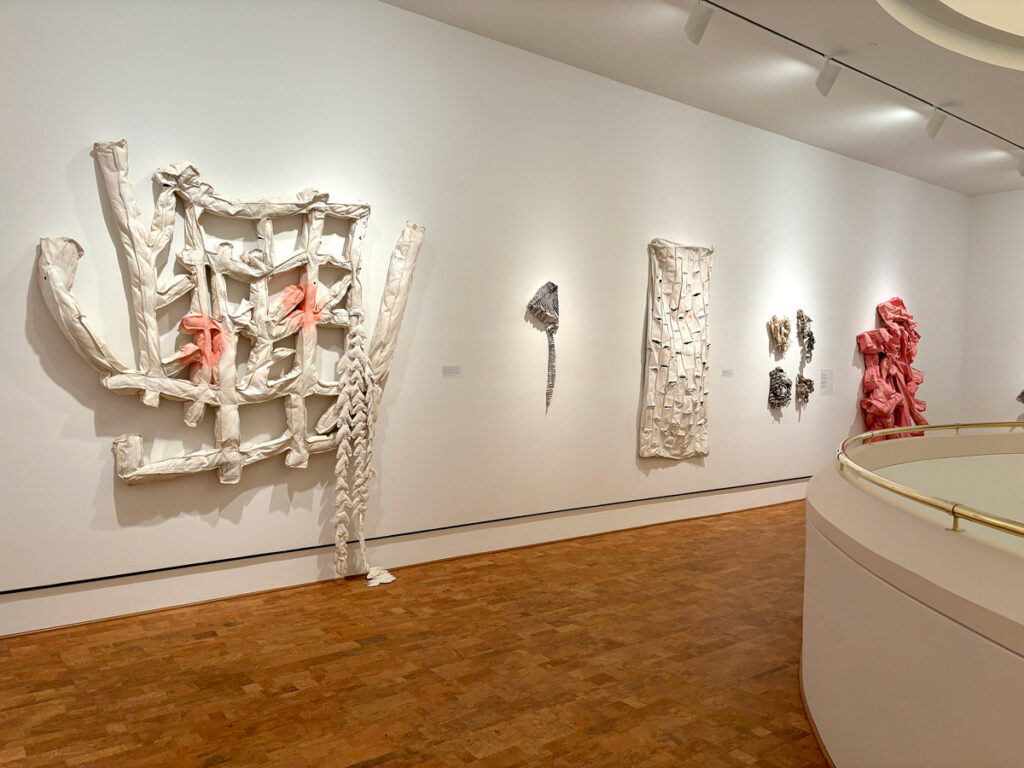 Gallery view of large-scale sculptural wall installations in white materials displayed in a contemporary museum space