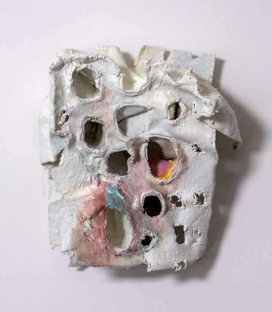 Abstract sculptural wall piece with organic texture and layered white and pink materials forming irregular openings