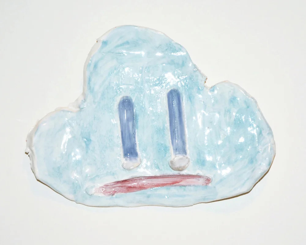 Glossy ceramic cloud wall piece with a neutral expression and soft blue tones