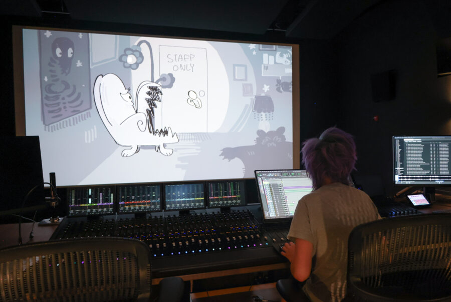 student at sound board looking at black and white animation on large screen